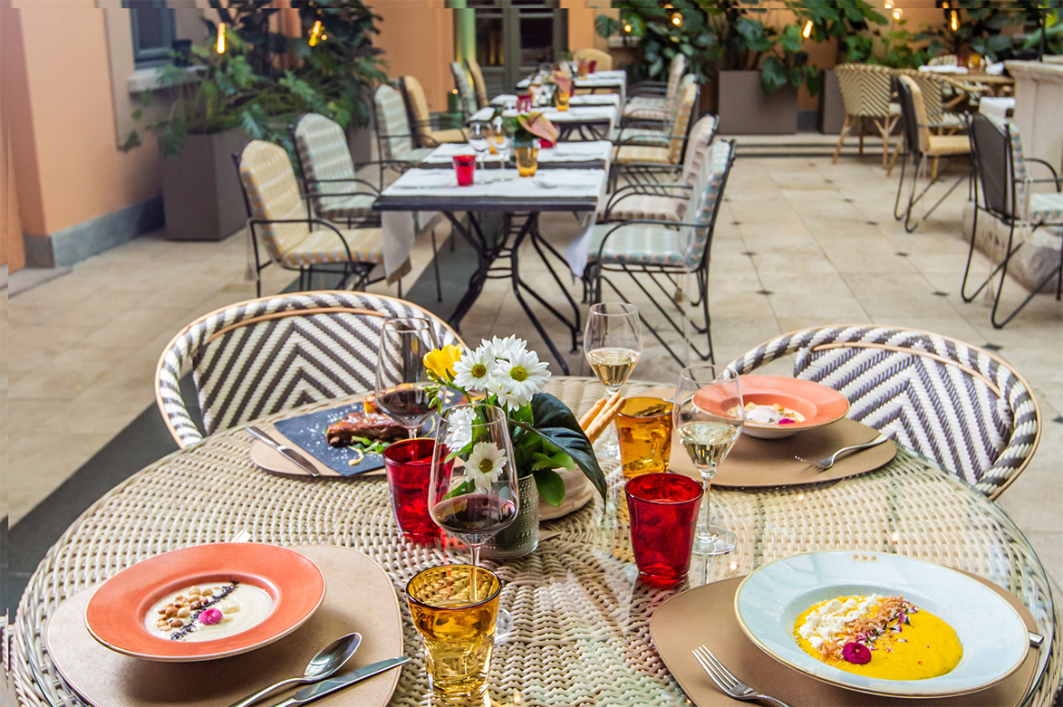 An outdoor restaurant table set with colorful plates glasses and a floral centerpiece